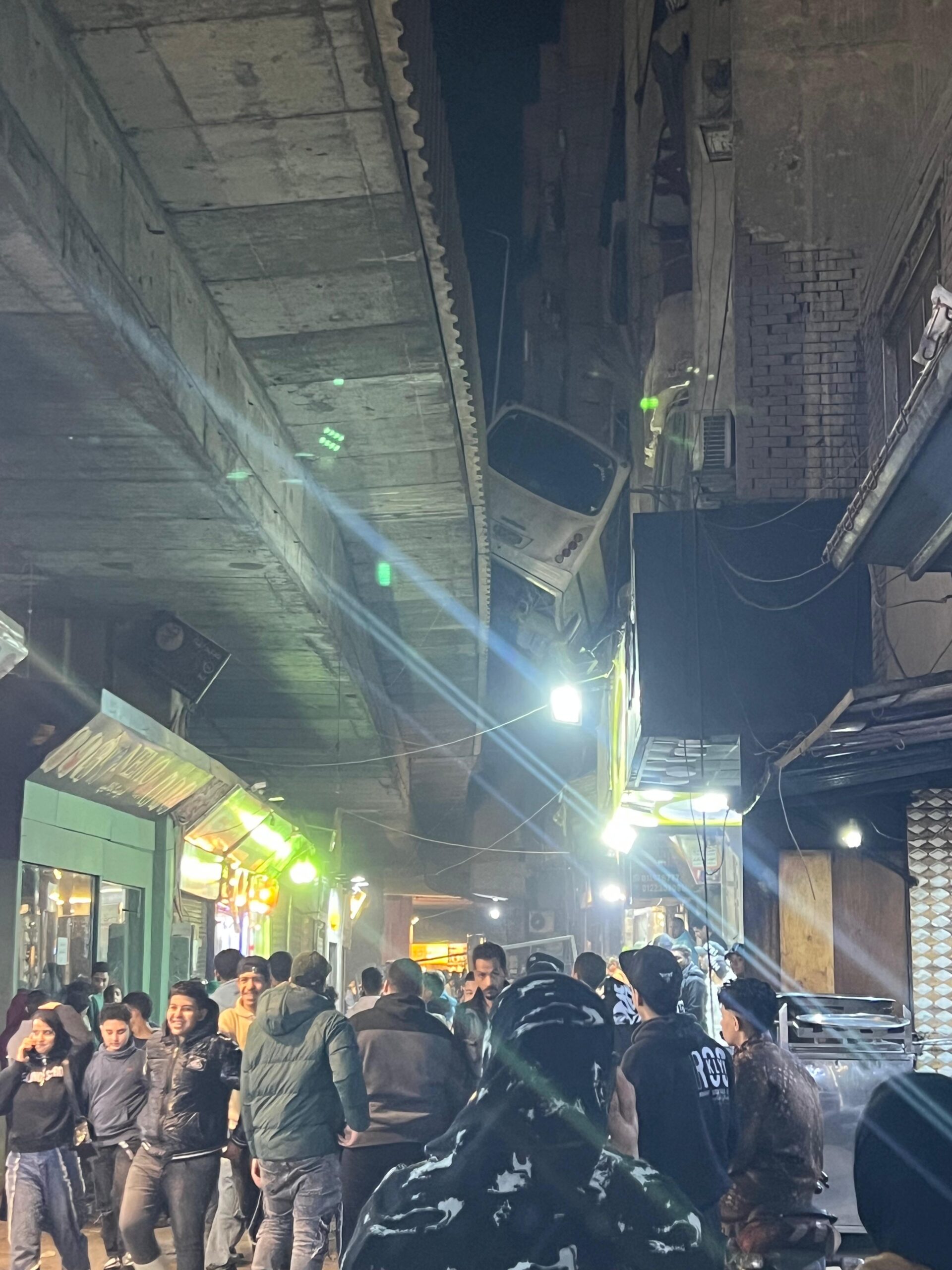 A shocking sight: bus caught between building and bridge in Giza